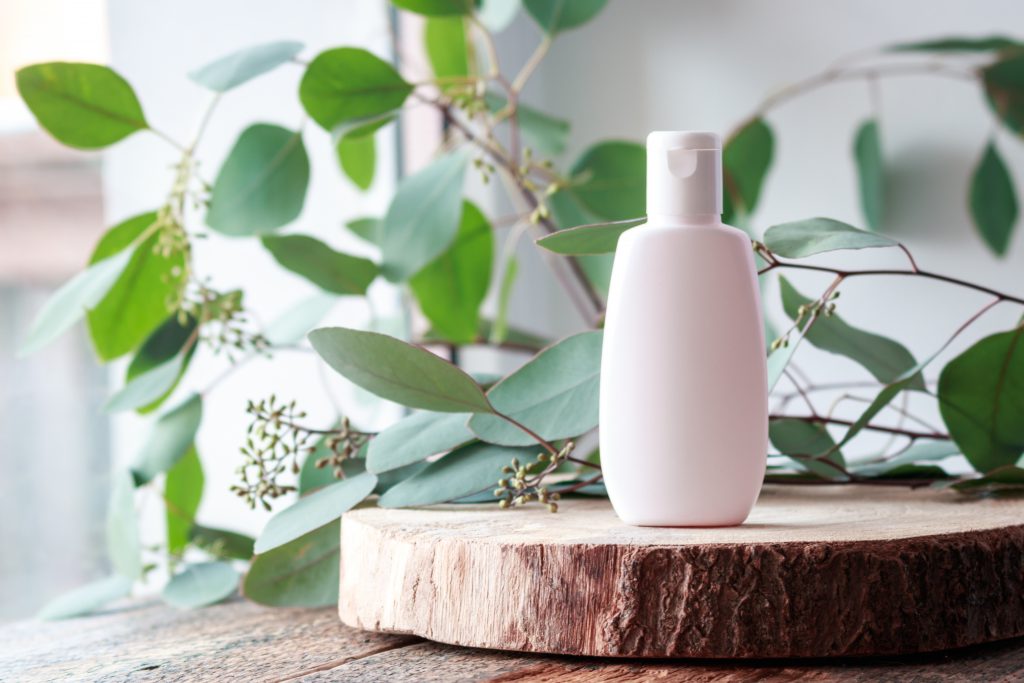 Cosmetic bottle with green leaves of eucalyptus.